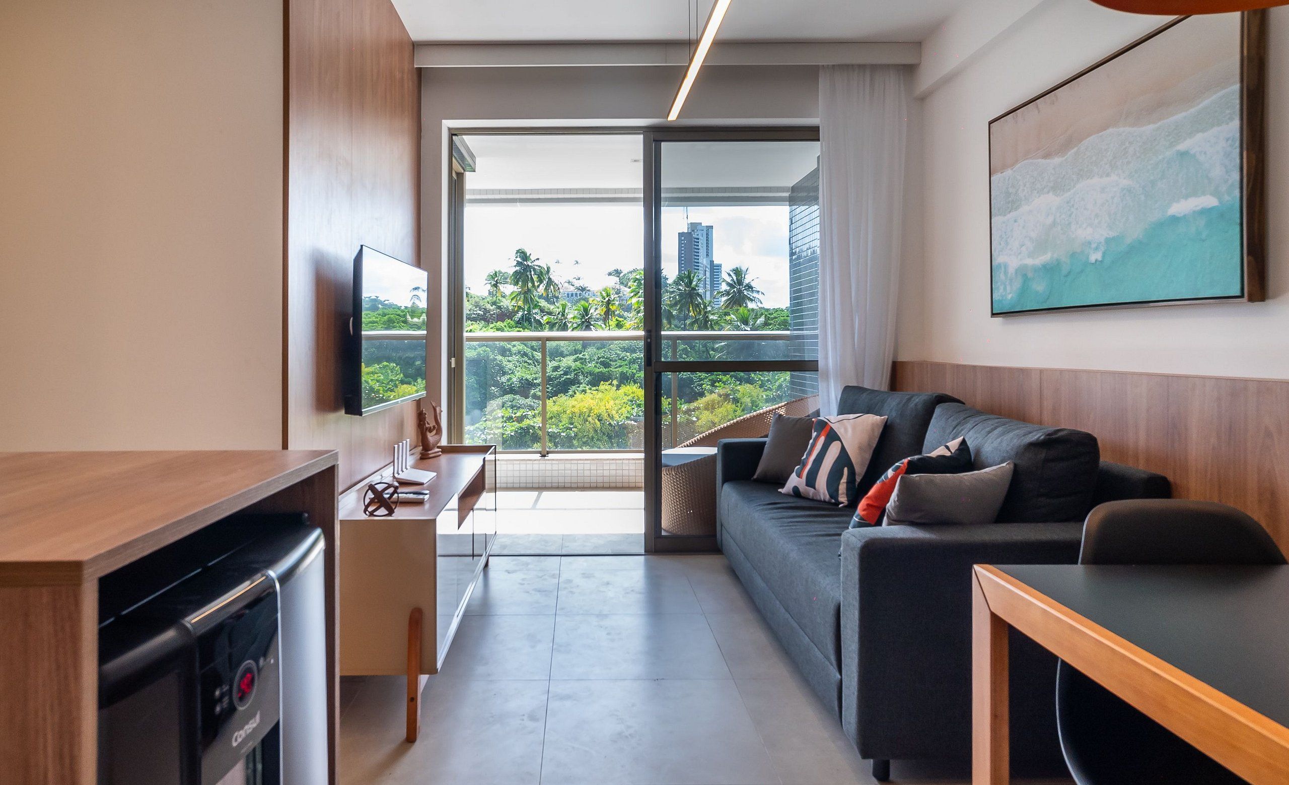 Una sala de estar moderna con un sofá, una mesa de centro, un televisor y una zona de cocina con lavavajillas.
