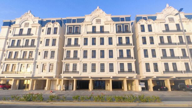 Um edifício de vários andares com fachada simétrica, apresentando uma entrada central com porta de vidro e uma placa acima.