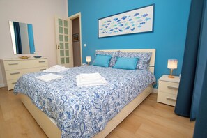 Un dormitorio con cama, mesita de noche, cómoda y puerta a otra habitación.