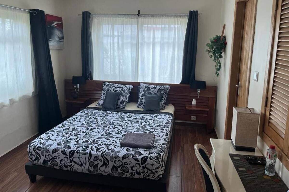 Un dormitorio ordenado con cama, mesitas de noche, escritorio y una silla.