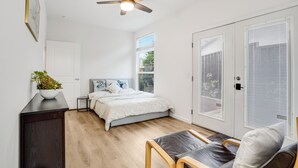 A bedroom with a bed, bedside tables, a ceiling fan, a window, and a door. - Privately Secluded 2-BR Guesthouse in Fremont (Fremont)
