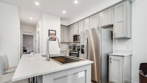 A modern kitchen with a central island, stainless steel appliances, and light grey cabinetry. - Privately Secluded 2-BR Guesthouse in Fremont (Fremont)