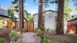 A residential property with a stone pathway leading to a white building, surrounded by large trees and potted plants. - Privately Secluded 2-BR Guesthouse in Fremont (Fremont)