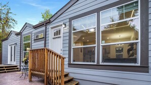A house with a wooden staircase leading to a deck, large windows, and a stone patio. - Privately Secluded 2-BR Guesthouse in Fremont (Fremont)