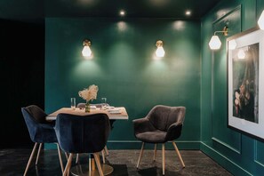 Un espace repas comprenant une table, des chaises et des lampes fixées au mur.