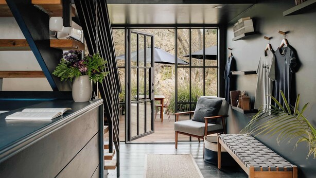 Ein modernes Interieur mit Treppe, einer Sitzecke und Blick durch große Fenster.