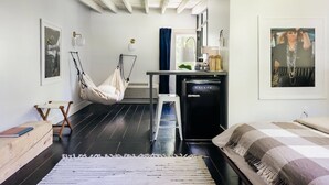 A compact room with a bed, a small desk, a hanging chair, and a compact kitchenette. - Coop 004 Summary:<br>Wel (Kenoza Lake)