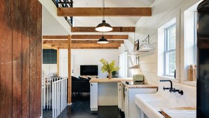 A modern kitchen with wooden beams, a white countertop, and a black faucet.