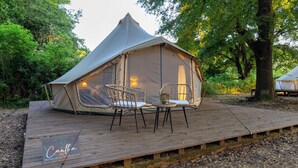 A tent with two chairs and a table on a wooden deck, surrounded by trees. - OAK glamping relax, CAUTHA cushy tent romantic and stylish, in a magical forest (Manziana)