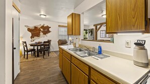 Una cocina moderna con armarios de madera, una isla grande con lavamanos y una zona de comedor con mesa y sillas.
