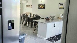 A modern kitchen with a central island, white cabinetry, and a ceiling fan. - Cozy 3-bedroom villa w/ AC, pool & unlimited beach access 10 mins from Ocho Rios (Saint Ann's Bay)