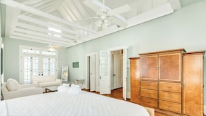 Un dormitorio amplio con una cama grande, un armario de madera y un ventilador de techo.