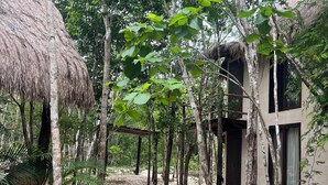 Un edificio rústico con techo de paja y terraza de madera rodeada de árboles.