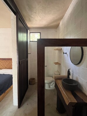 A compact bathroom with a wooden vanity, a round sink, and a toilet. - Cabins nestled in the heart of the Mayan jungle in Tulum, featuring a cenote-style pool (Francisco Uh May)