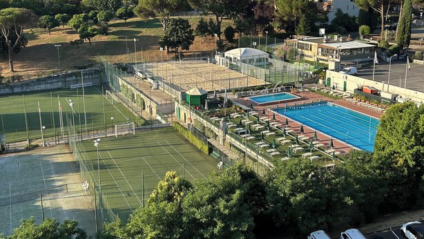 Un complexe sportif comprenant un court de tennis, une piscine et un petit pavillon.