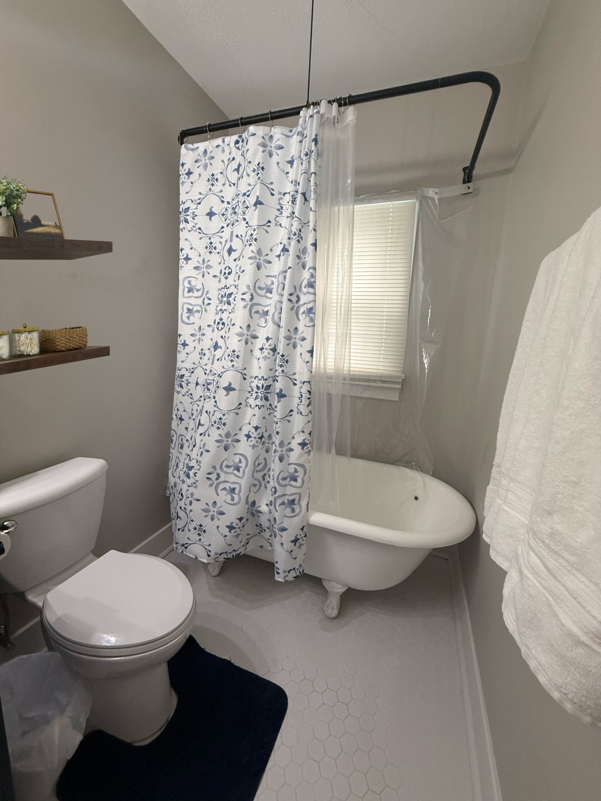 Ein Badezimmer mit Toilette, Badewanne, Duschvorhang, einem Fenster und einem Handtuchhalter.
