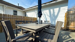 A wooden patio table with chairs, a lantern, and an umbrella.