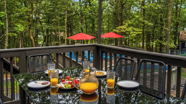 An outdoor dining table with chairs, a pitcher of orange juice, and a plate of food. - Night Golf, Fire Pit, Game Room, Hot Tub, Theater room, Lake Access Fun house! (East Stroudsburg)