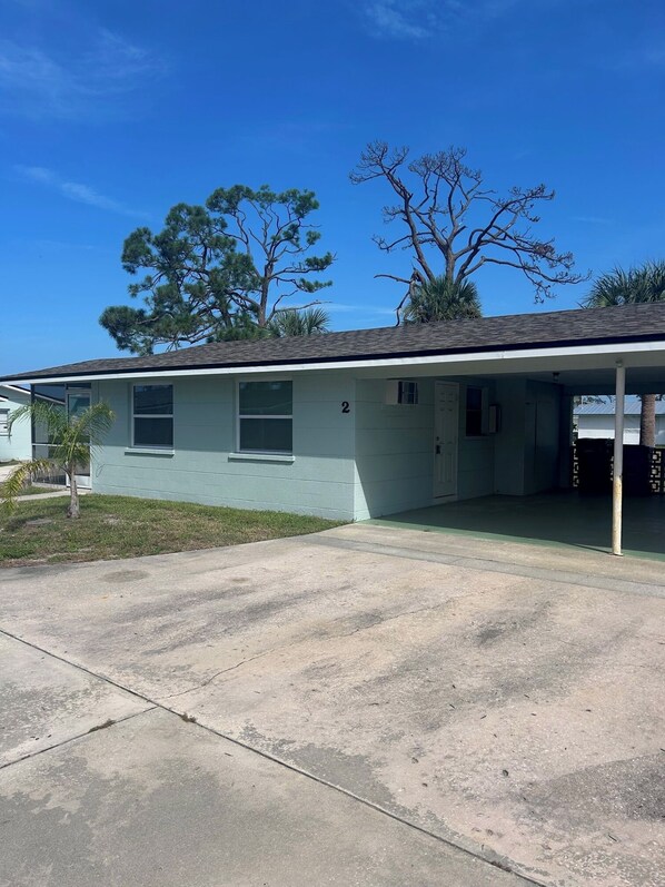 Ein Bungalow mit Veranda, Garage und kleinem Vorgarten.