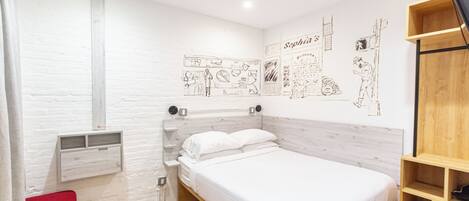 Un dormitorio con cama, una silla roja, un estante de madera y una pared con bocetos.