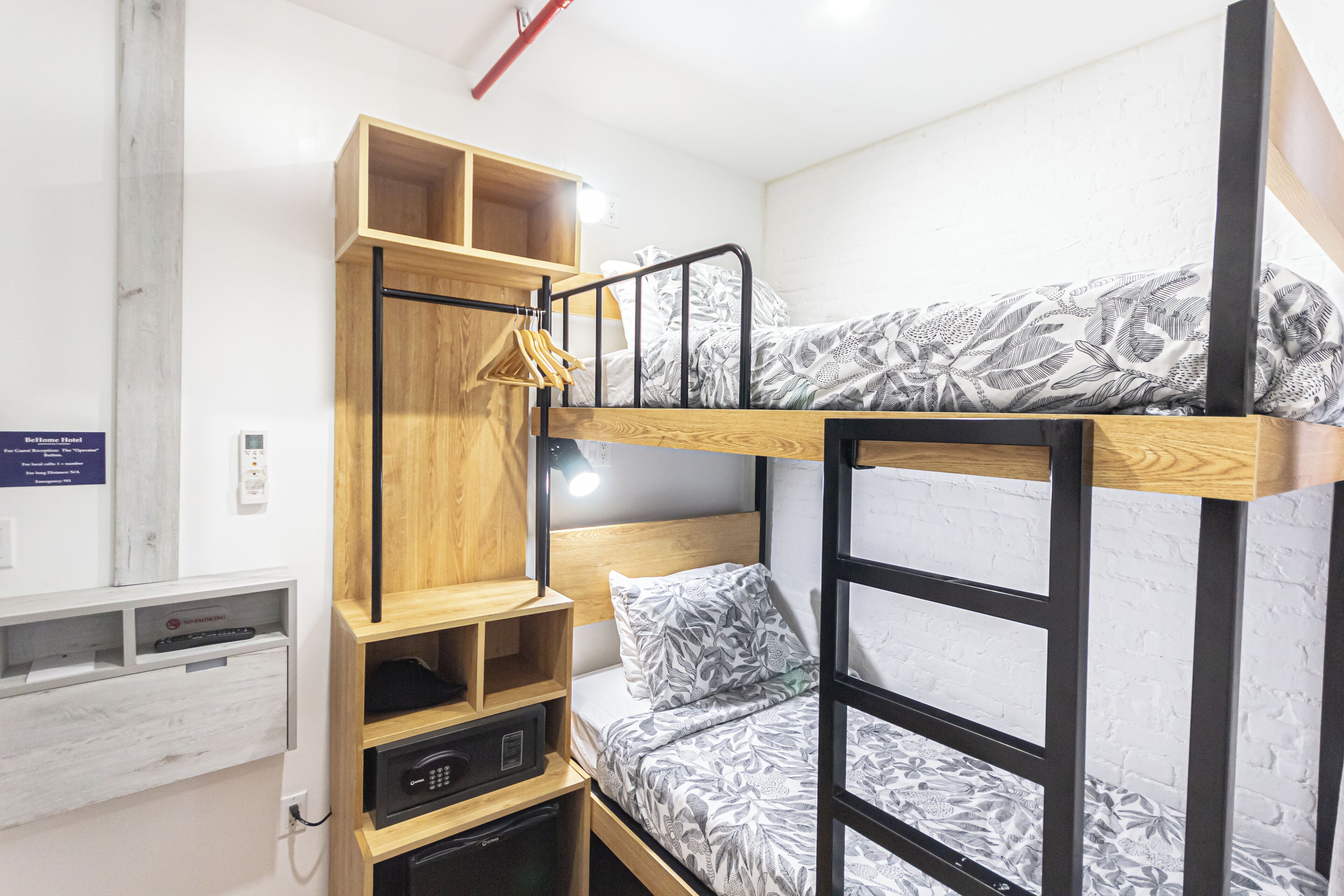 A bunk bed with a wooden headboard, a desk with a chair, and a shelf unit.