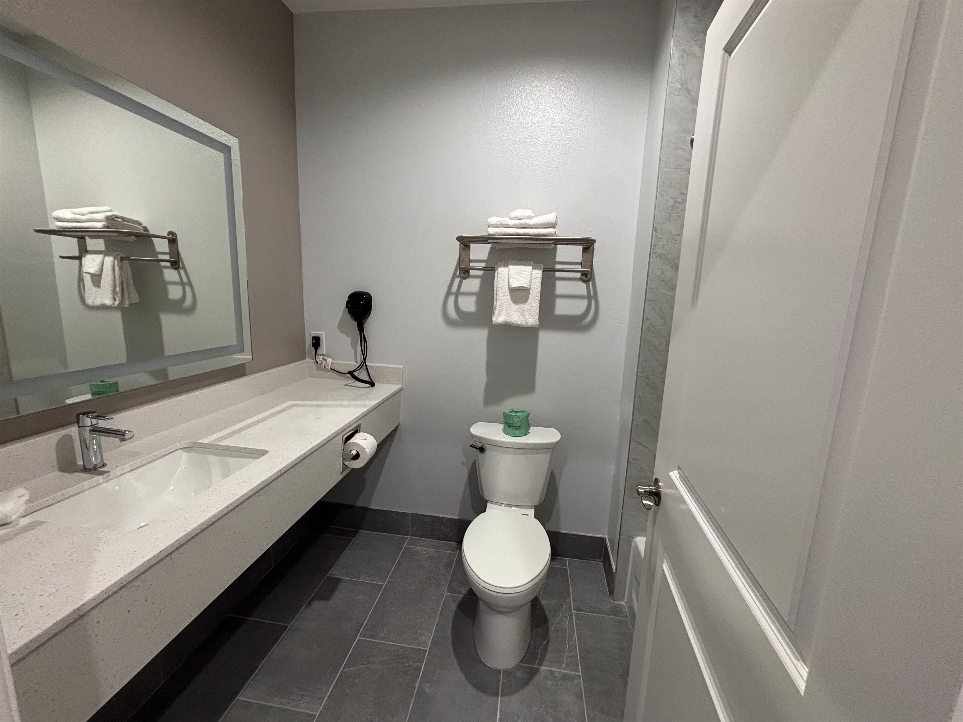 Un baño con un lavamanos blanco, un inodoro y un perchero para toallas.