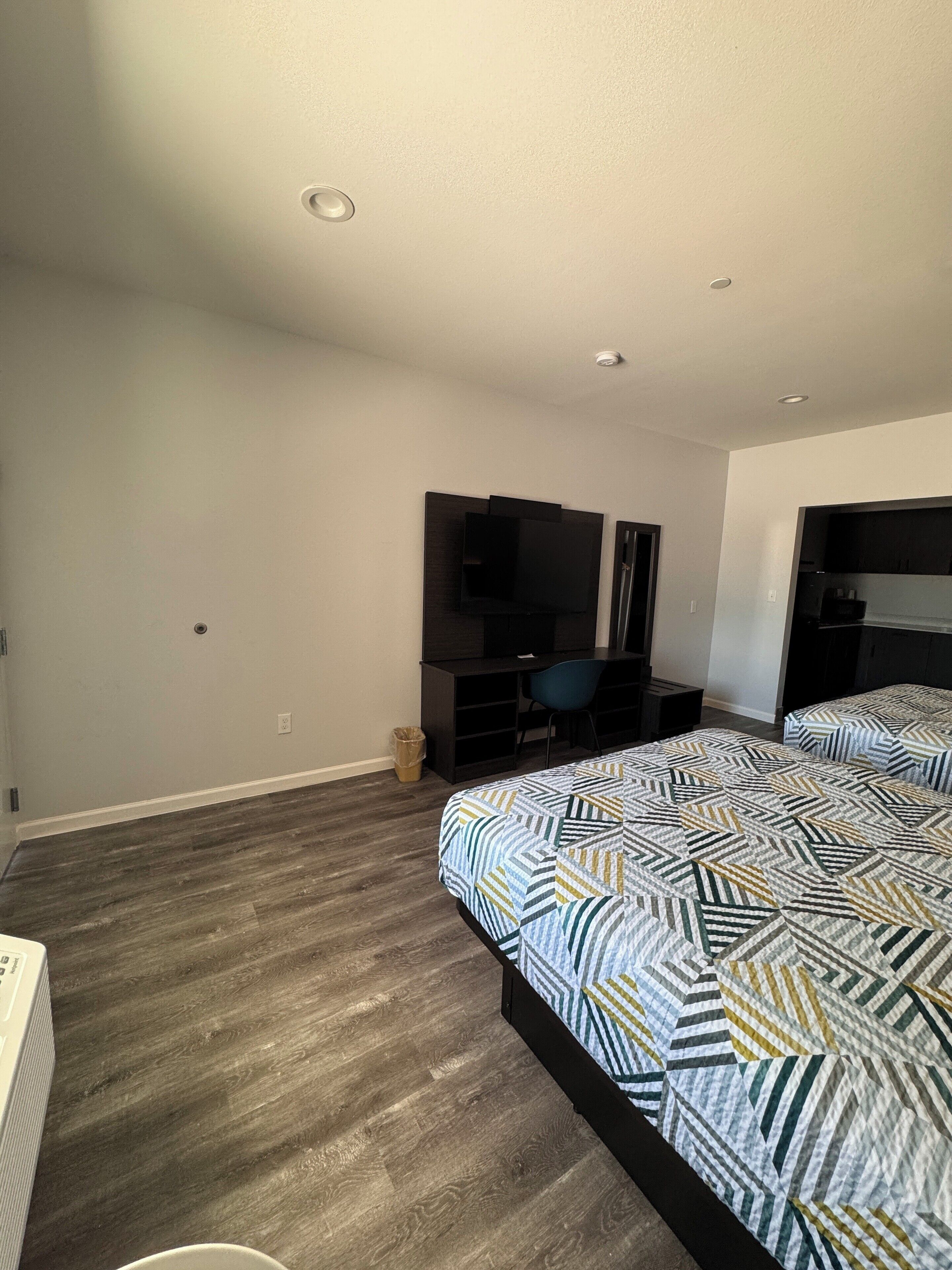 A bedroom with a bed, a desk, and a TV.