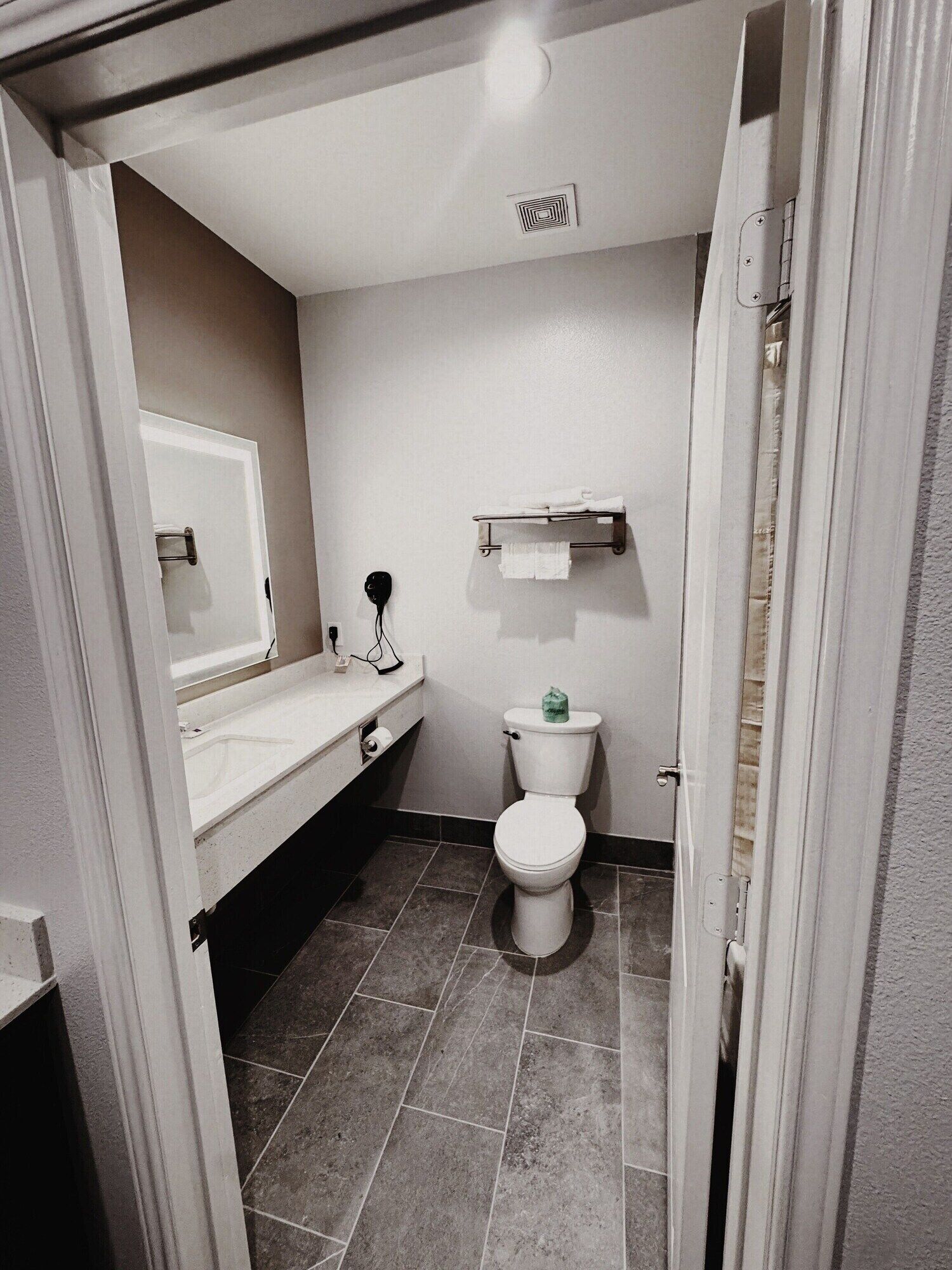 Un baño pequeño con inodoro, lavamanos y espejo.