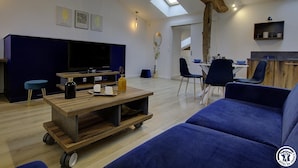 A modern living room with a large flat-screen TV, a wooden coffee table, and a blue sofa.