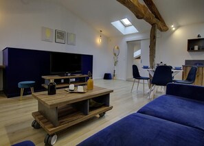 A modern living room with a large flat-screen TV, a wooden coffee table, and a blue sofa.
