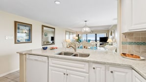 A modern kitchen with white cabinetry, a granite countertop, and a built-in dishwasher.