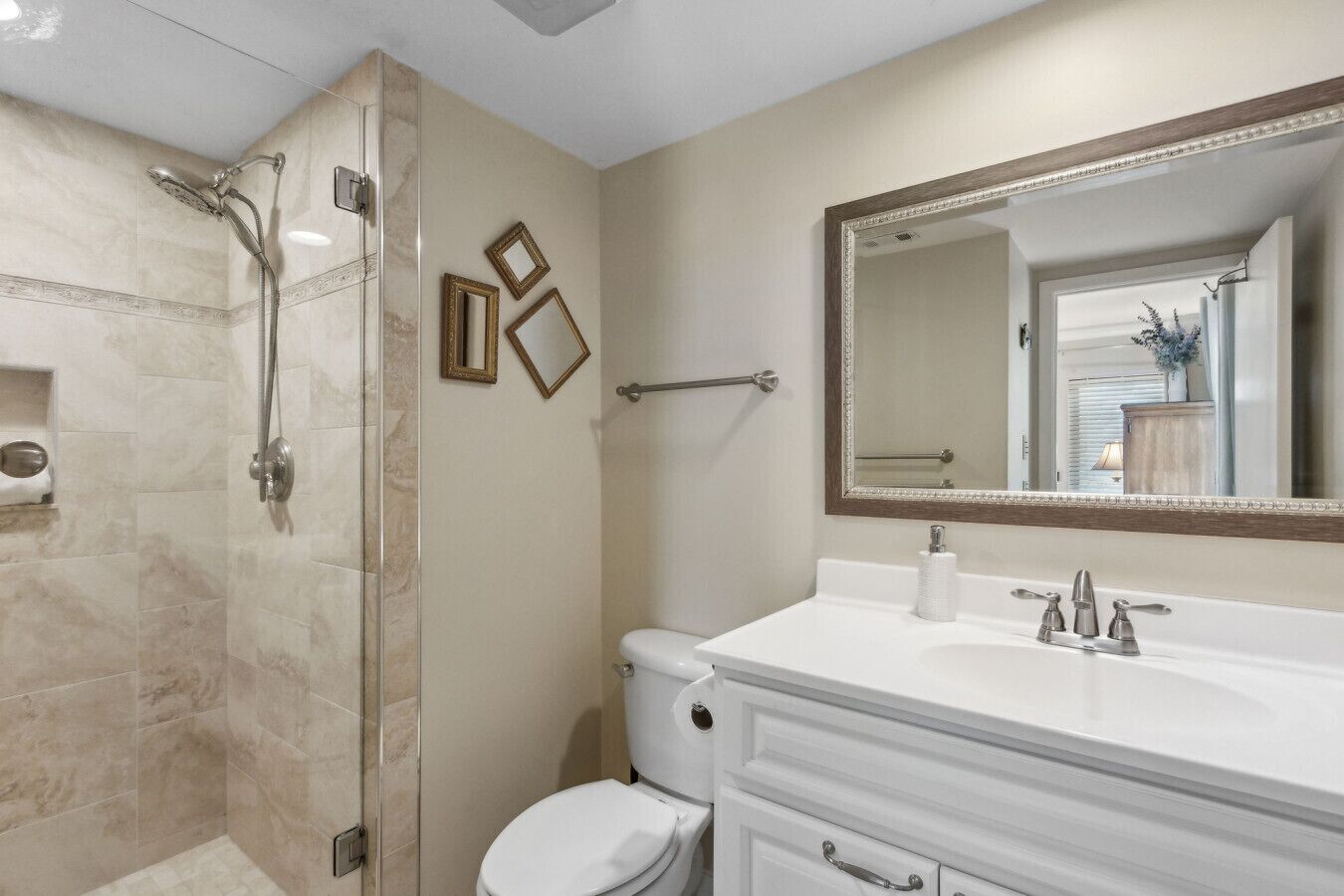 A bathroom with a shower, toilet, vanity, and a large mirror.