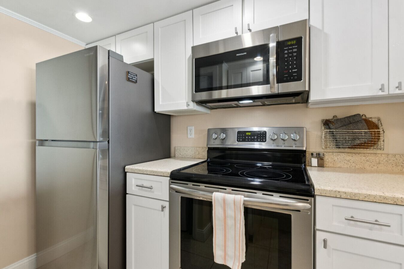 A kitchen with white cabinets, a stainless steel refrigerator, a microwave, and an oven.