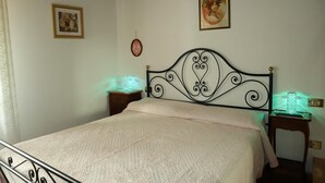 A bedroom with a bed, two bedside tables, and a wall-mounted light fixture. - Casa Linda a window to the sea (Sant' Anna di Stazzema)