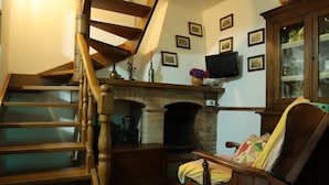 A wooden staircase leading to a living room with a fireplace, a television, and a cabinet with glass doors. - Casa Linda a window to the sea (Sant' Anna di Stazzema)