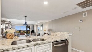 A kitchen with a double sink, white cabinetry, and a dishwasher.