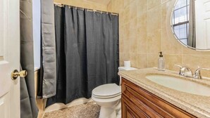 A bathroom with a toilet, a sink with a mirror, and a shower curtain. - Studio Across the Street from Convention Center 2R (Philadelphia)