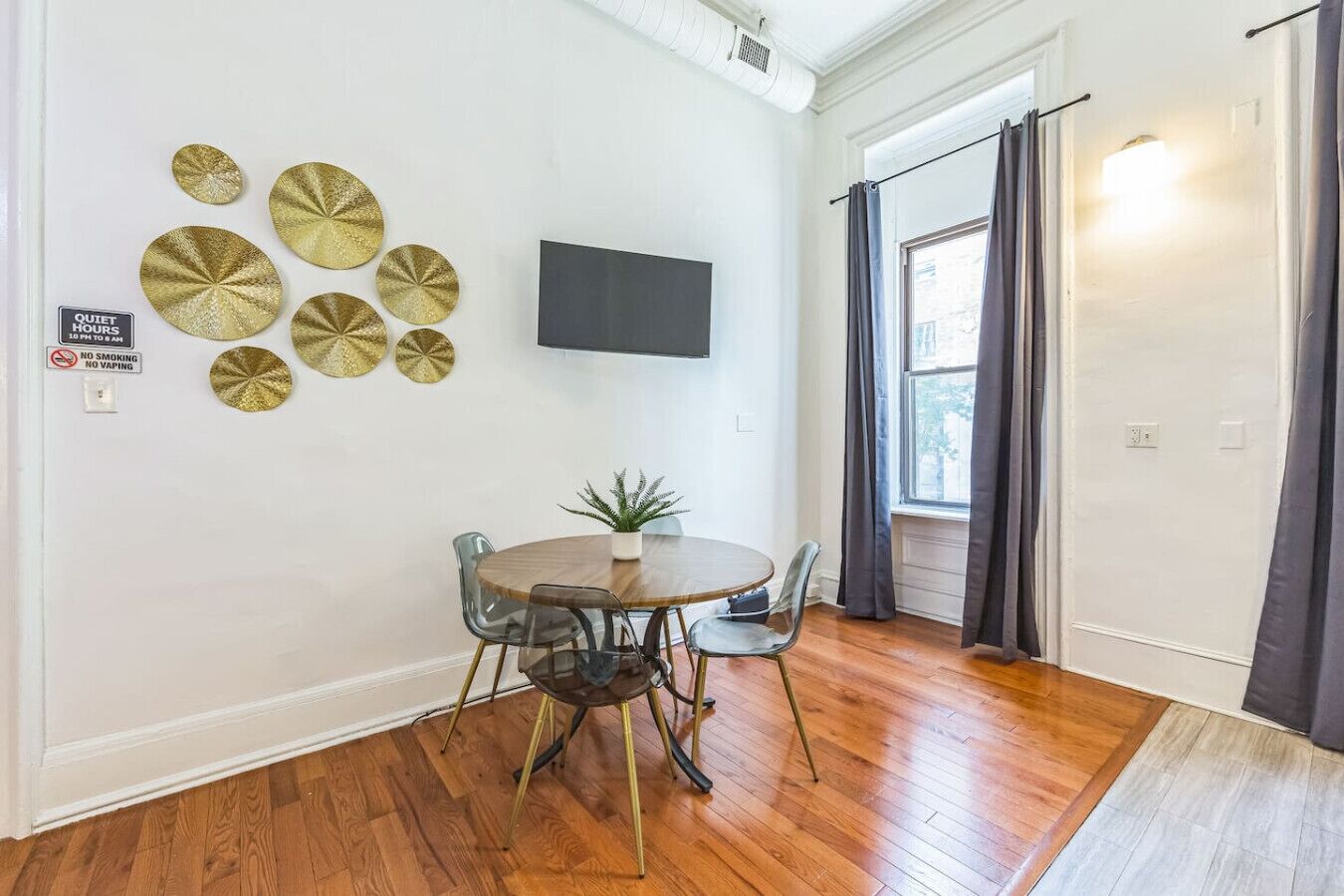 A dining area with a round table, chairs, and decorative plates on the wall.