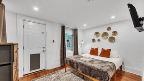 A bedroom with a bed, a wardrobe, a door, and a window.