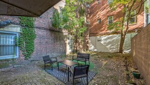 A courtyard with a brick wall, a table with chairs, and a patterned rug.