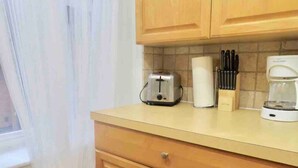 Una cucina con mobili in legno, un tostapane, una macchina da caffè e un portachiodi.