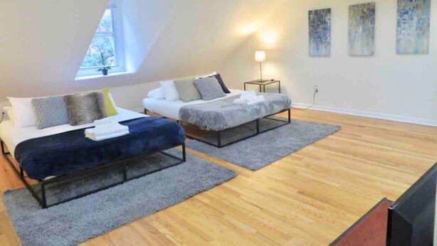 Camera da letto mansarda moderna con due letti, un lucernario e opere d'arte alle pareti.