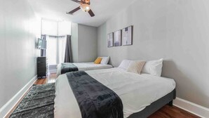 Un dormitorio moderno con dos camas, un ventilador de techo y vistas al exterior.