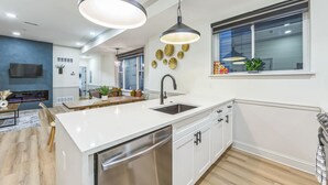 A modern kitchen with white cabinetry, a stainless steel dishwasher, and pendant lighting. - New 2/2 Across from Fairmount Park | 10 mins to DT (Philadelphia)