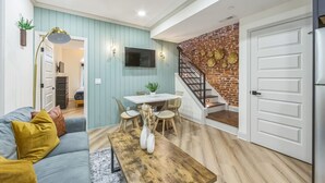 Uma sala de estar moderna com uma parede azul, uma mesa de centro de madeira, um sofá e uma área de jantar com mesa e cadeiras.