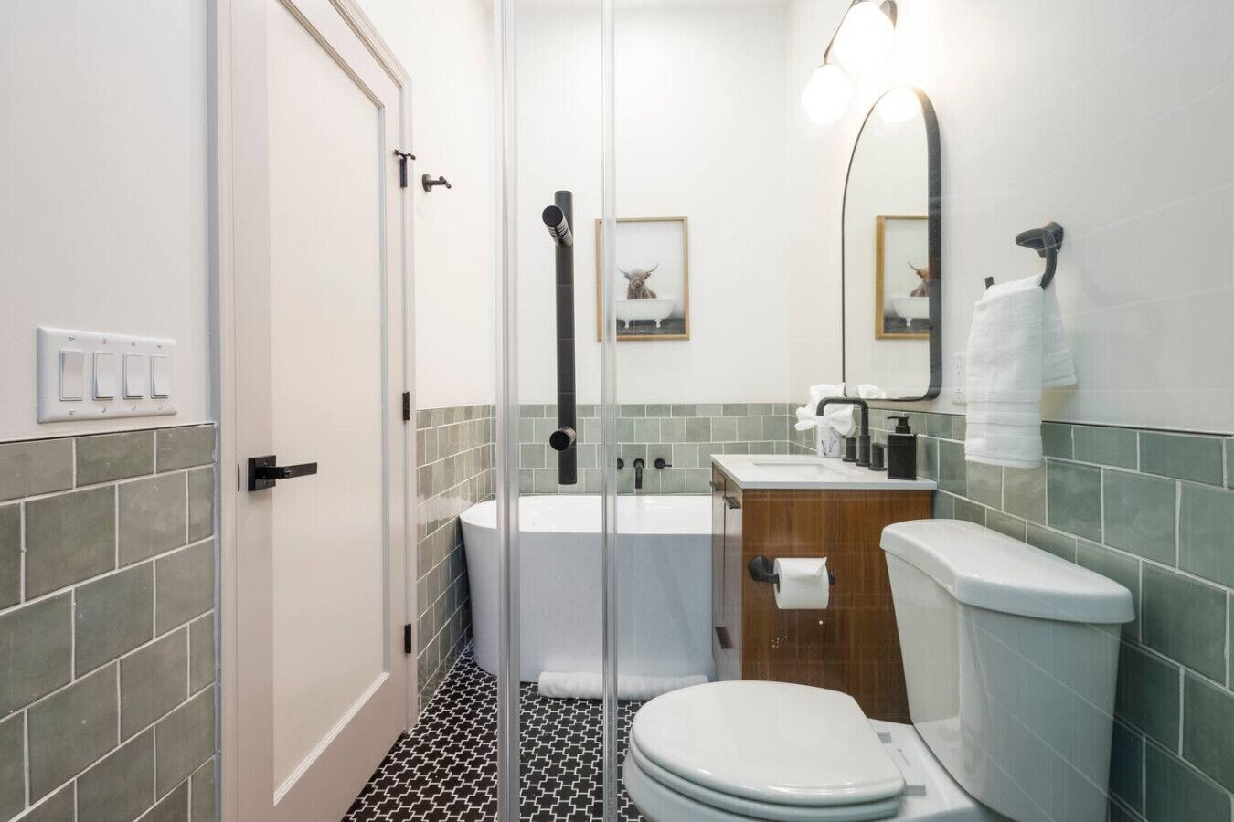 A modern bathroom with a glass shower enclosure, a bathtub, a toilet, and a sink with a mirror above.