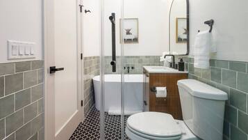 A modern bathroom with a glass shower enclosure, a bathtub, a toilet, and a sink with a mirror above.