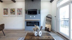 Una sala de estar moderna con chimenea, obras de arte y un ventanal grande.