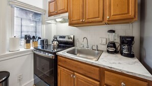 A kitchen with wooden cabinets, a stainless steel stove, a sink, and a coffee maker.