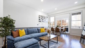 A living room with a sectional sofa, a coffee table, and a dining area with chairs. - 2BR w/Balcony Fairmount Park 10 mins to DT (Philadelphia)